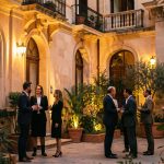 Soirée culturelle à Barcelone, façade éclairée aux tons dorés, spectateurs élégants dans une cour méditerranéenne, ambiance chaleureuse au crépuscule.